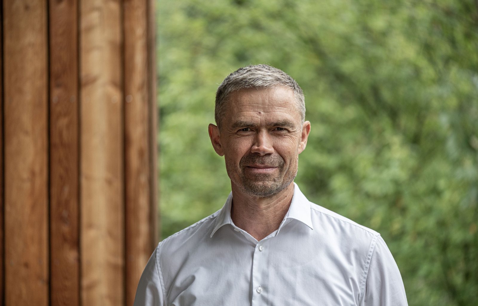 Peter Faistnauer vor einer Holzfassade, im Hintergrund Bäume